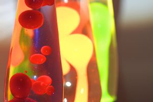 Three half lava lamps diagonally offset one behind the other, focus on the cutout of the first. First red lava, second orange, third green